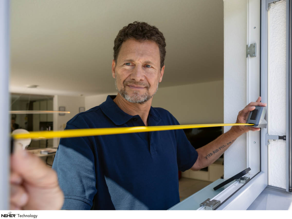 Insektenschutz. Ein Mann nimmt Aufmaß am Fenster.